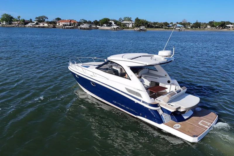 Slide: The Image of 2016 Regal 35 Sport Coupe cruising on a serene lake with scenic shoreline views. - 22