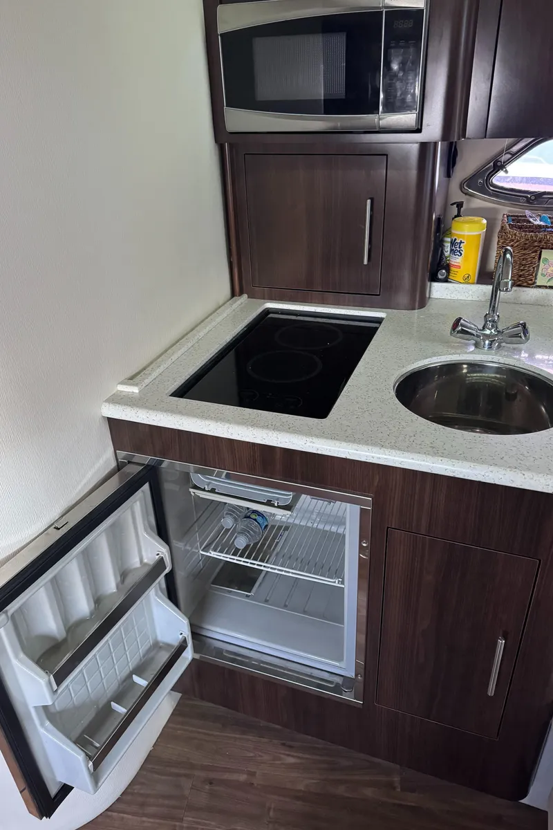 Slide: The Image of Compact kitchen in a 2016 Regal 35 Sport Coupe with microwave, sink, and open fridge. - 49