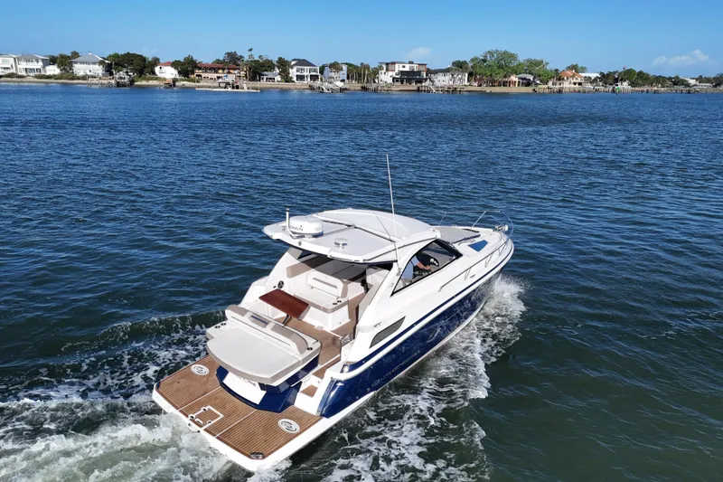 Slide: The Image of 2016 Regal 35 Sport Coupe cruising on a scenic waterway near coastal homes. - 67