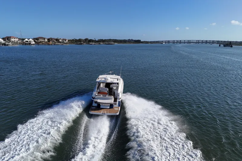 Slide: The Image of 2016 Regal 35 Sport Coupe cruising on open water with scenic bridge view. - 69