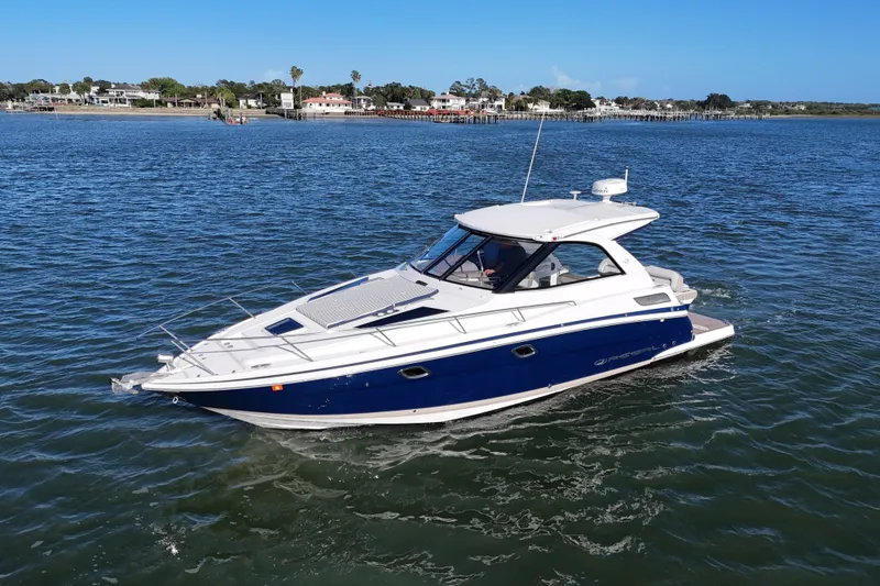 Slide: The Image of 2016 Regal 35 Sport Coupe cruising on a serene lake with scenic shoreline views. - 7