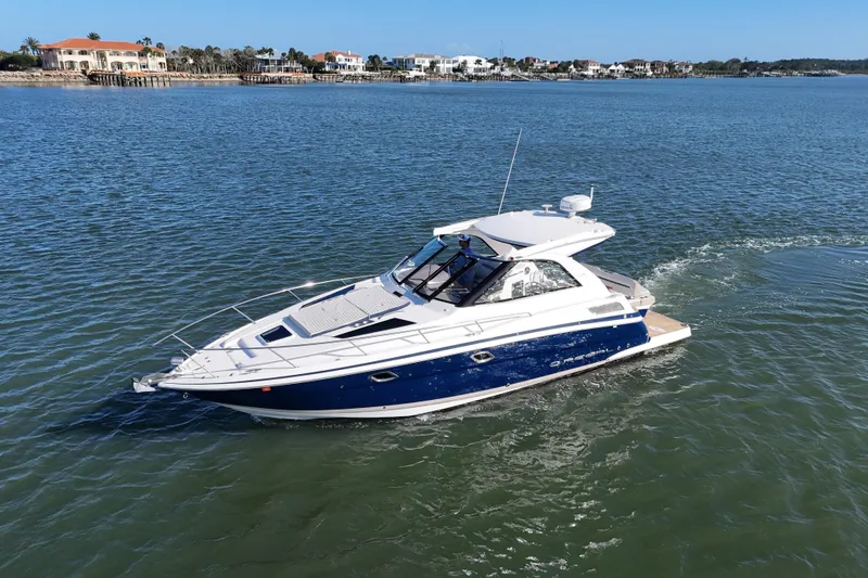 Slide: The Image of 2016 Regal 35 Sport Coupe cruising on a serene waterway near luxury waterfront homes. - 74