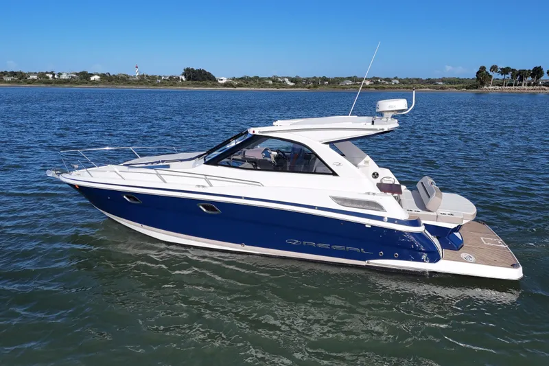 Slide: The Image of 2016 Regal 35 Sport Coupe boat cruising on a calm lake under a clear blue sky. - 76