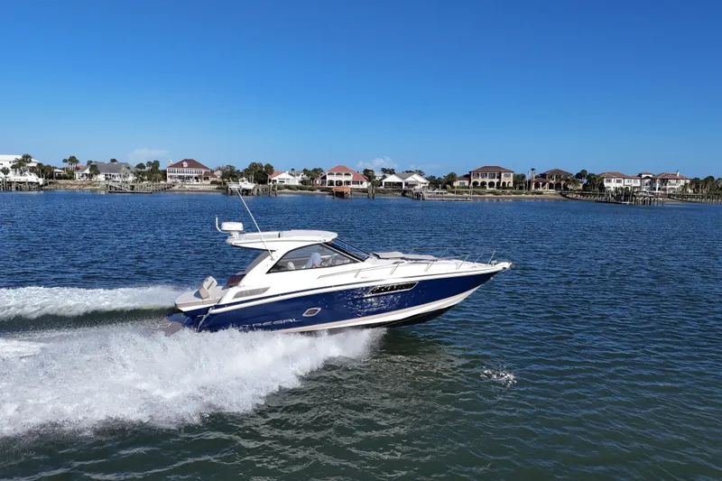 Slide: The Image of 2016 Regal 35 Sport Coupe cruising on a sunny day near waterfront homes. - 8