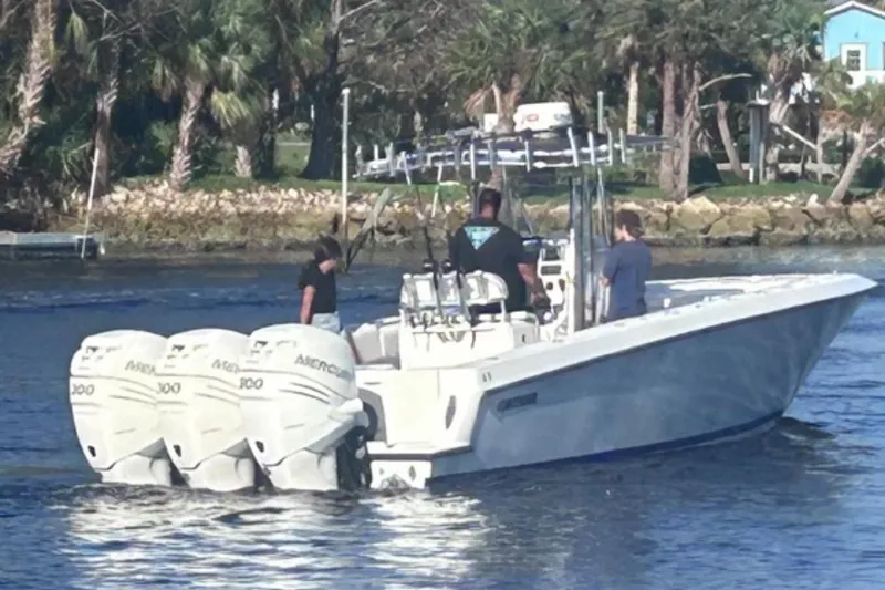 Slide: The Image of 2005 Contender 35 ST boat with triple Mercury engines on a calm waterway. - 2