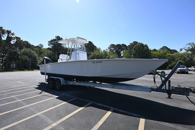 Slide: The Image of 2017 Rambo 27 boat on trailer in parking lot, surrounded by trees. - 16