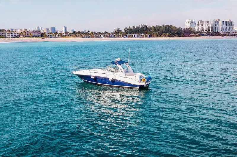 Slide: The Image of 2005 Sea Ray 340 Sundancer yacht on calm ocean near city shoreline. - 2