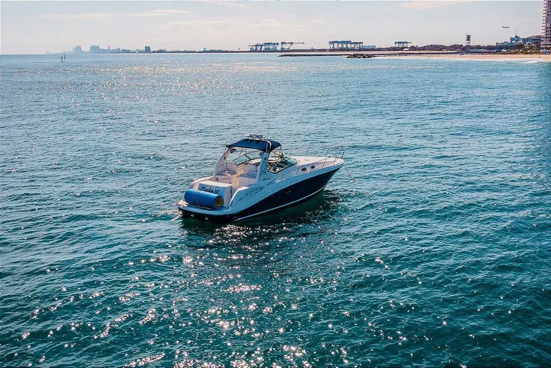 Slide: The Image of 2005 Sea Ray 340 Sundancer yacht cruising on open water near coastline. - 5