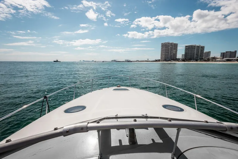 Slide: The Image of 2005 Sea Ray 340 Sundancer cruising towards a coastal skyline under a partly cloudy sky. - 7