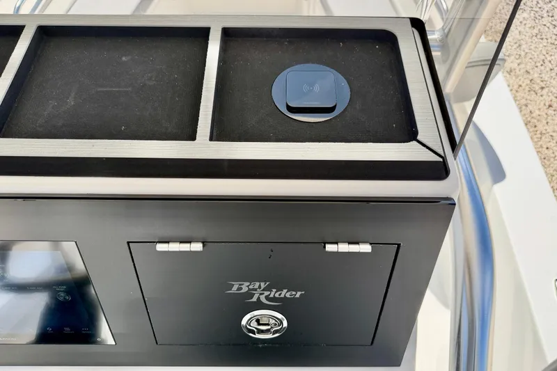 Slide: The Image of 2026 Bay Rider 219 Bay boat console with storage compartment and wireless charging pad. - 21