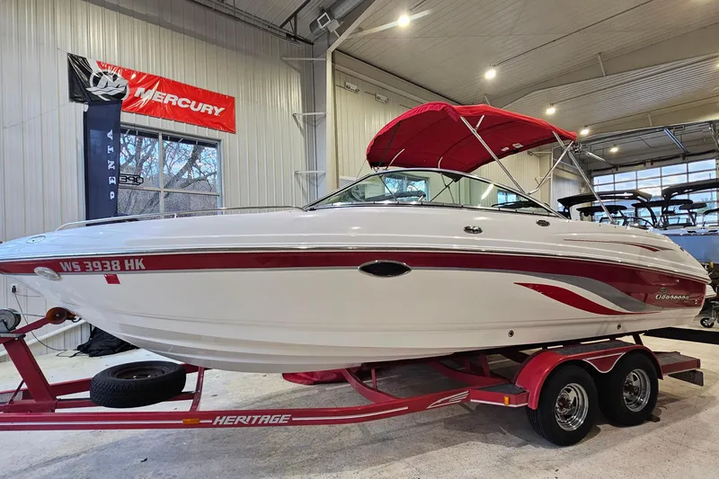 The Image of 2000 Chaparral 230 SSi boat with red accents on a trailer in a showroom. - 1