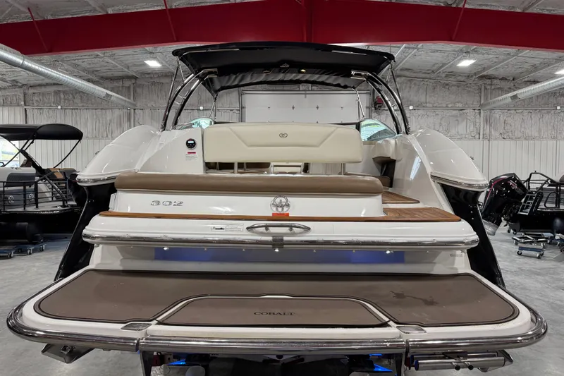 Slide: The Image of 2015 Cobalt 302 boat rear view in a showroom with red beams. - 5