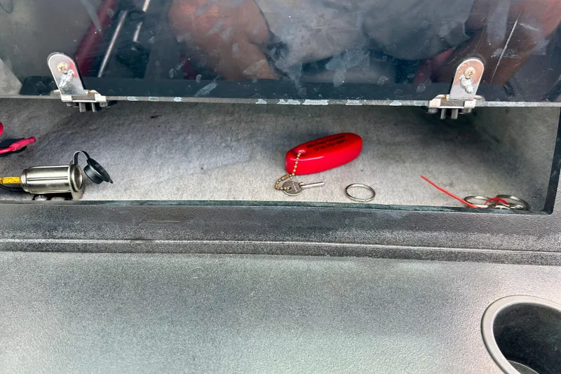 Slide: The Image of Open glove compartment in a 1994 Stratos 290 Ski-N-Fish boat with keys and accessories. - 50