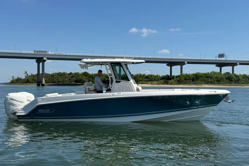Slide: The Image of 2023 Boston Whaler 280 Outrage boat cruising under a bridge on a sunny day. - 2
