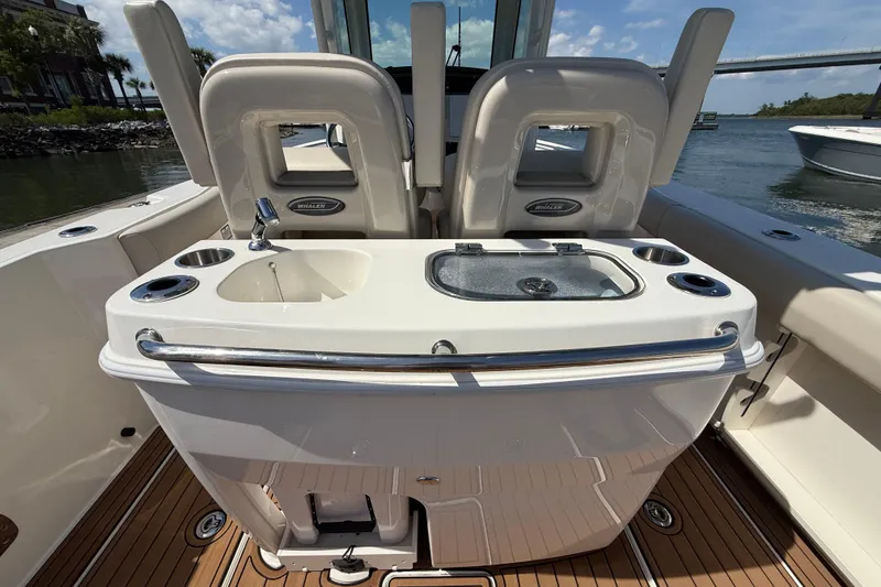 Slide: The Image of 2023 Boston Whaler 280 Outrage boat interior with seating and sink, docked by the water. - 26