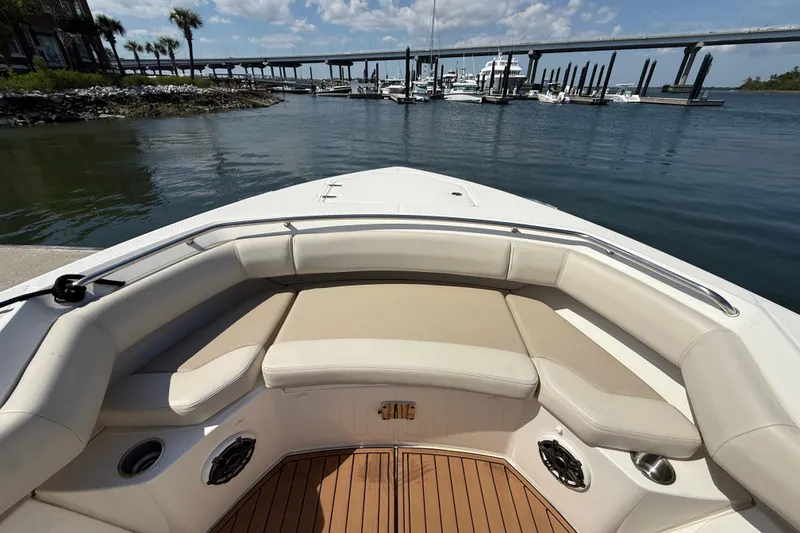 Slide: The Image of 2023 Boston Whaler 280 Outrage boat interior with cushioned seating, docked near a marina. - 30