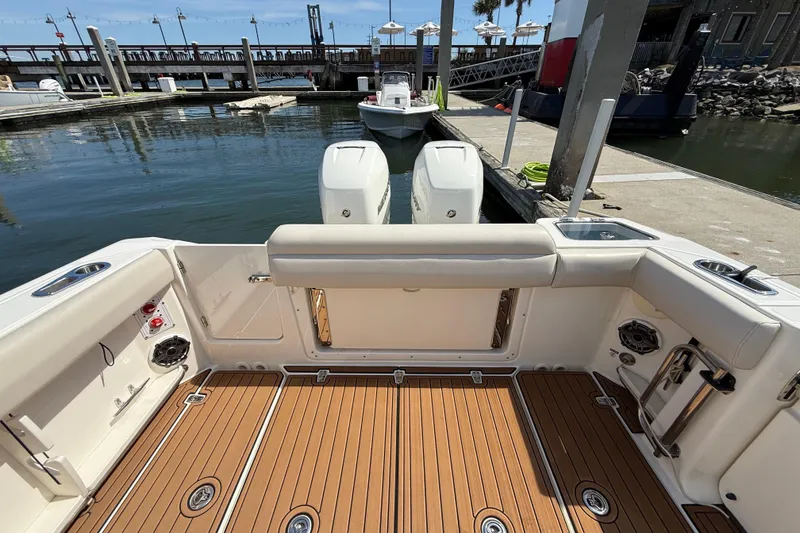 Slide: The Image of 2023 Boston Whaler 280 Outrage boat interior with teak flooring at a marina dock. - 31