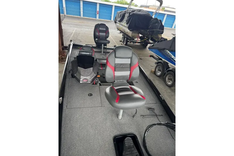 Slide: The Image of 2021 Ranger RT178 boat interior with gray and red seating, parked in storage facility. - 28
