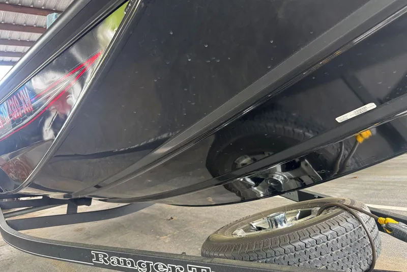 Slide: The Image of 2021 Ranger RT178 boat on trailer, black hull, under a metal roof. - 45