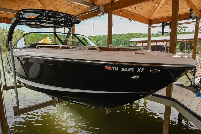 The Image of 2022 Chaparral 307 SSX boat docked under wooden shelter on a lake. - 0
