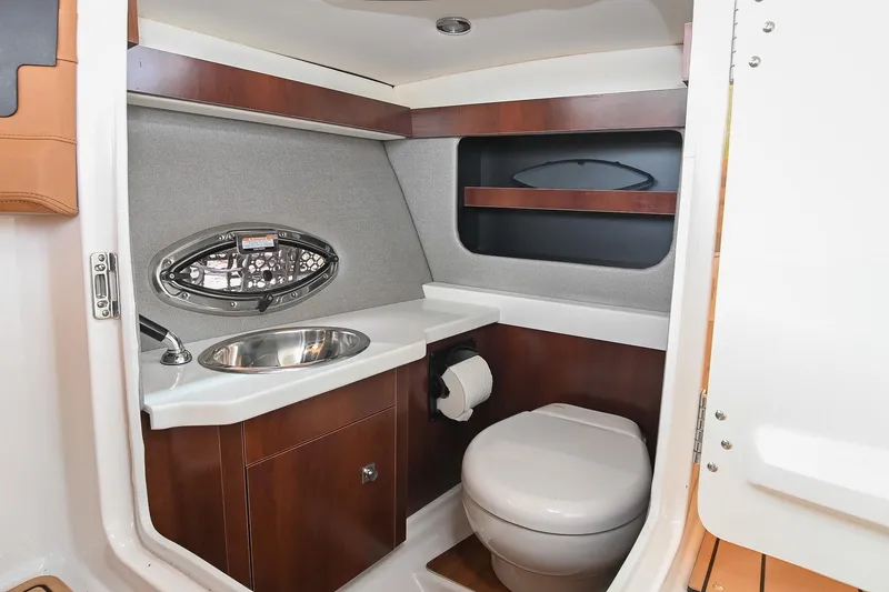 Slide: The Image of 2022 Chaparral 307 SSX boat bathroom with sink, toilet, and wooden cabinetry. - 27