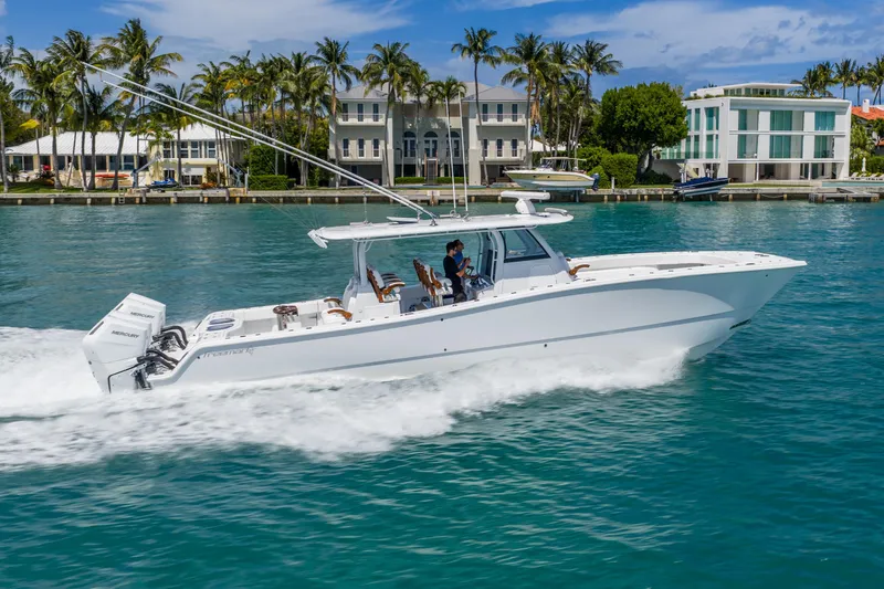 Slide: The Image of 2025 Freeman 43 boat cruising on clear blue water near luxury waterfront homes. - 4