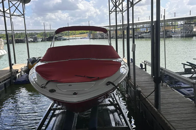 Slide: The Image of 2005 Sea Ray 200 Select boat docked with red cover under a marina. - 6