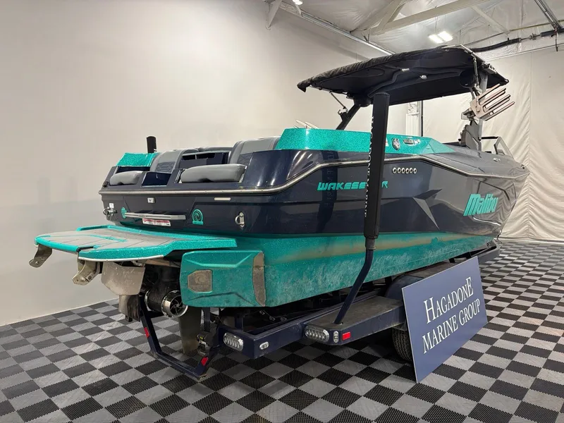 Slide: The Image of 2023 Malibu 26 LSV boat in showroom, turquoise and black. - 3