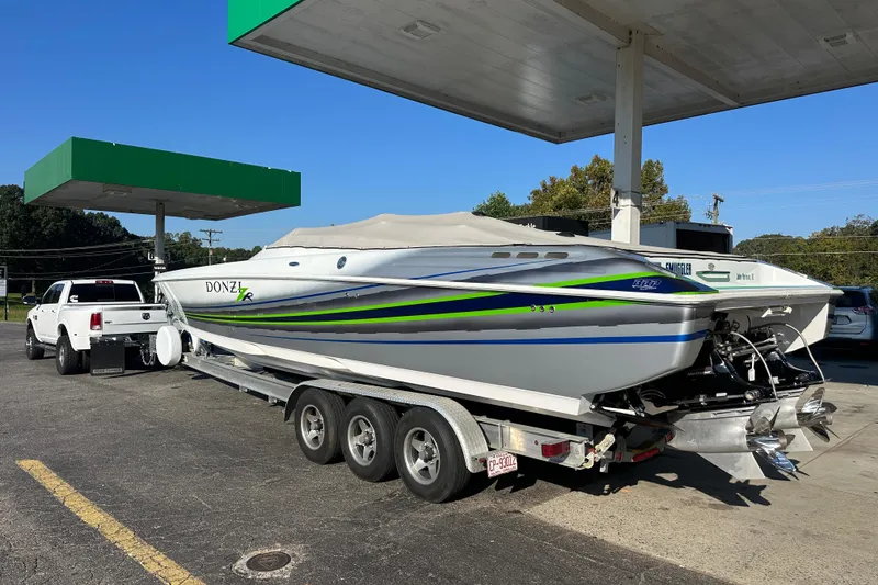Slide: The Image of 2007 Donzi 35 ZR boat on trailer at gas station, white truck towing. - 7