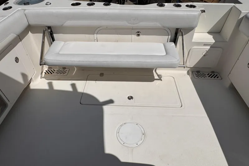 Slide: The Image of 2015 Sailfish 320 CC boat interior with foldable bench seat and storage compartments. - 13