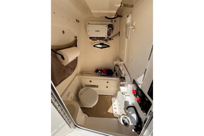 Slide: The Image of 2015 Sailfish 320 CC boat interior with toilet, storage, and Fusion audio system. - 20