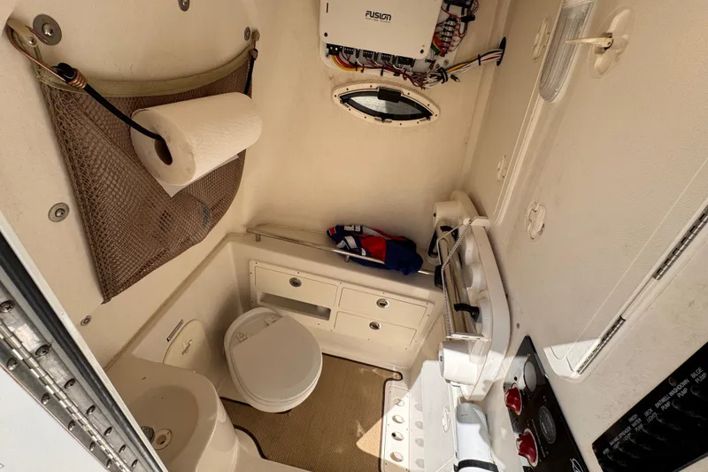 Slide: The Image of Interior of a 2015 Sailfish 320 CC boat featuring a compact bathroom setup. - 21