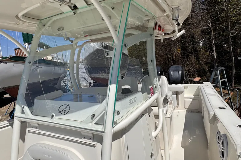 Slide: The Image of 2015 Sailfish 320 CC boat interior with console and seating, docked outdoors. - 25