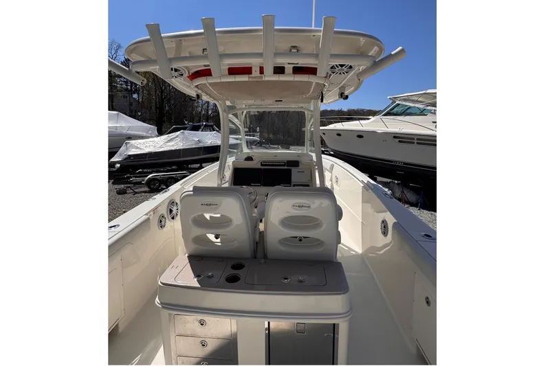 Slide: The Image of 2015 Sailfish 320 CC boat interior with seating and storage, docked under clear blue sky. - 7