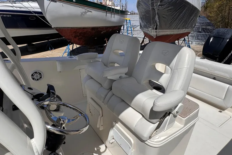 Slide: The Image of 2015 Sailfish 320 CC boat interior with white leather seats and steering wheel. - 8