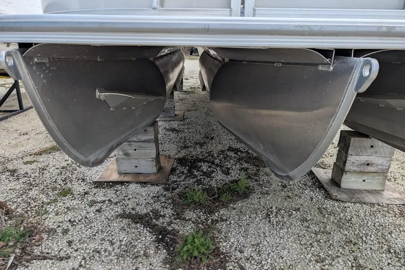 Slide: The Image of 2022 Nepallo 22QL pontoon boat hulls on wooden supports, gravel ground. - 22