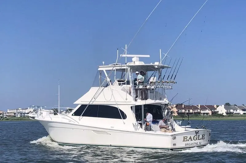 The Image of 2005 Egg Harbor 43 SportYacht cruising on water, featuring fishing rods and a clear sky. - 1