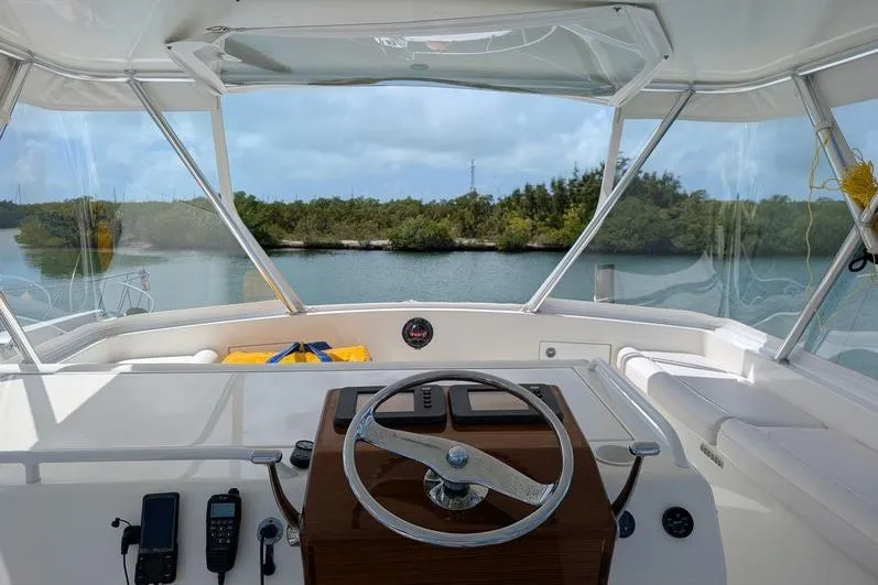 Slide: The Image of Helm of 2005 Egg Harbor 43 SportYacht overlooking serene waterway and lush greenery. - 20