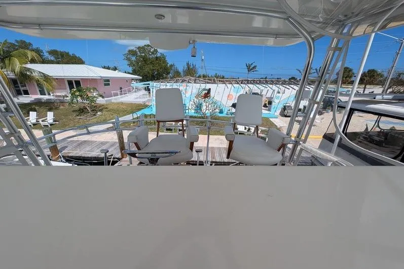 Slide: The Image of 2005 Egg Harbor 43 SportYacht helm with white chairs, docked near tropical setting. - 96
