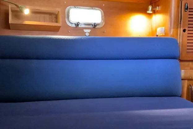 Slide: The Image of Cozy interior of 1995 Freedom 35 sailboat with blue seating and wooden accents. - 11