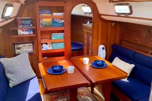 Slide: The Image of Cozy 1995 Freedom 35 yacht interior with wooden dining area and blue seating. - 9