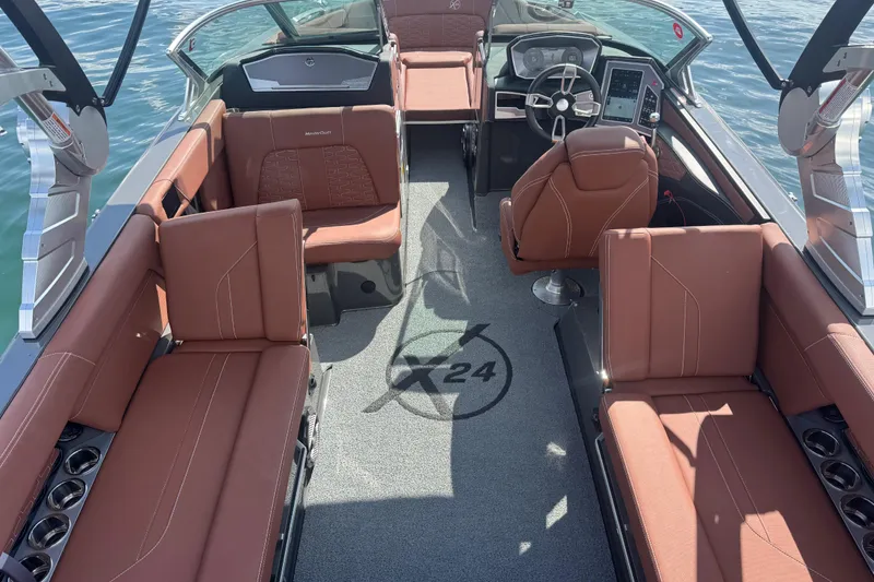 Slide: The Image of 2021 MasterCraft X24 boat interior with brown seating and modern dashboard on water. - 13