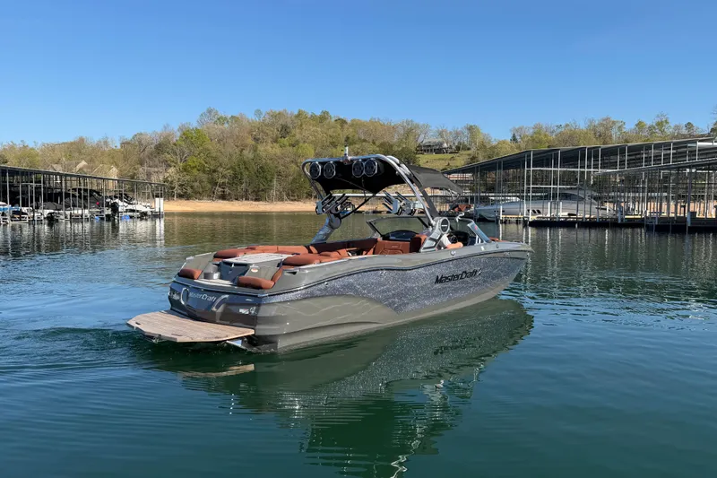 Slide: The Image of 2021 MasterCraft X24 boat on a serene lake near a marina. - 2