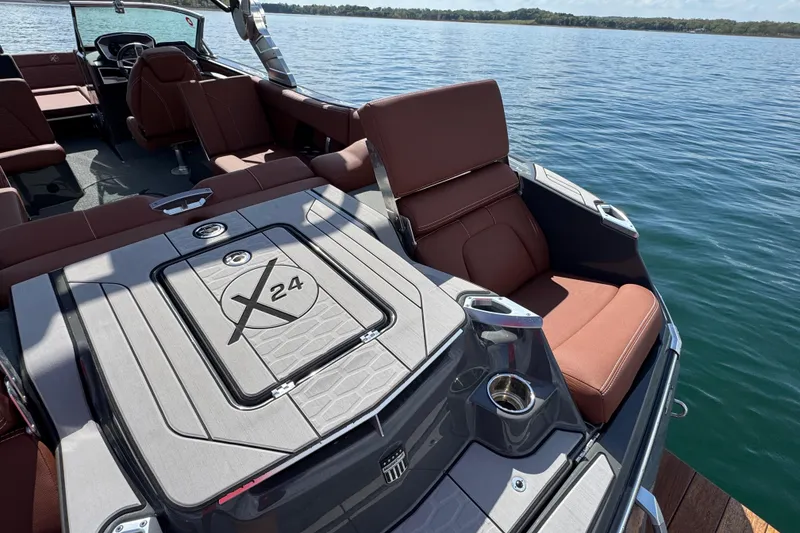 Slide: The Image of 2021 MasterCraft X24 boat interior with brown seating on a lake. - 21
