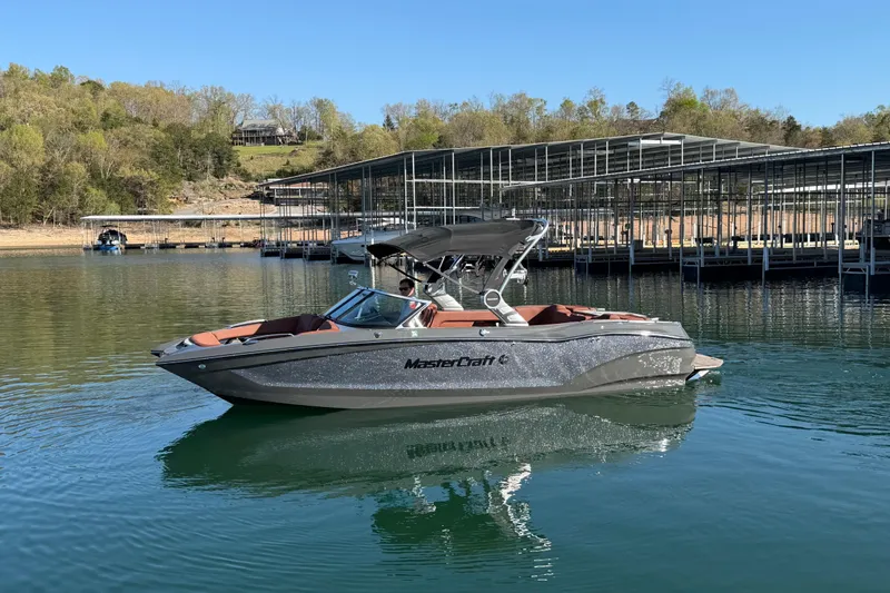 Slide: The Image of 2021 MasterCraft X24 boat on a calm lake near a marina. - 3