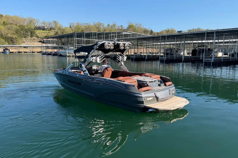 Slide: The Image of 2021 MasterCraft X24 boat docked on a serene lake with clear blue skies. - 5