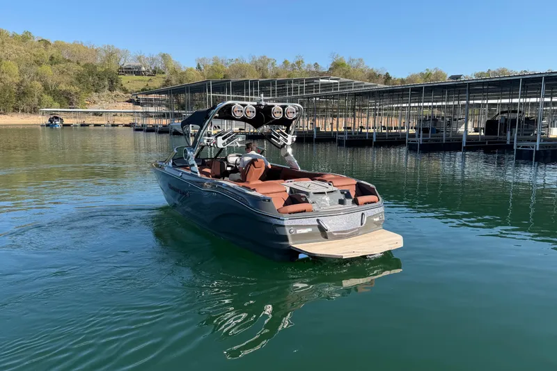 Slide: The Image of 2021 MasterCraft X24 boat on a serene lake near a marina. - 6
