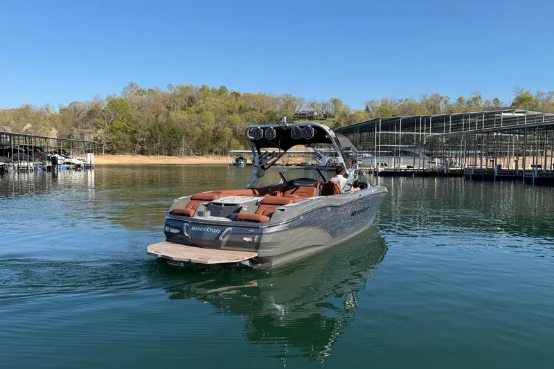 Slide: The Image of 2021 MasterCraft X24 boat on a serene lake near a marina. - 7