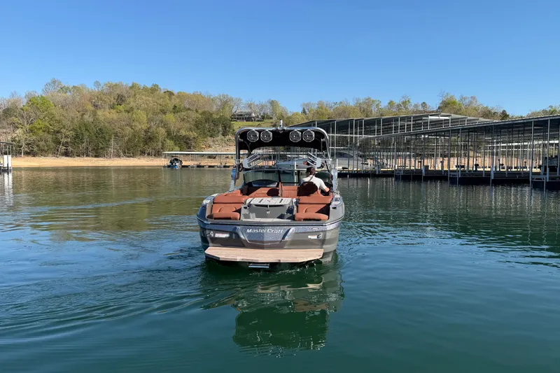 Slide: The Image of 2021 MasterCraft X24 boat on a serene lake near a marina. - 8