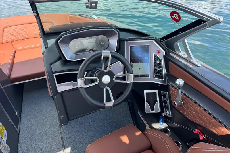 Slide: The Image of 2021 MasterCraft X24 boat interior with modern dashboard and steering wheel on water. - 9